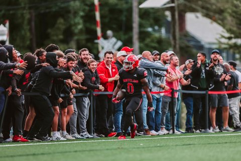 A Montclair football player, #0, is hyped up by a crowd of fans.