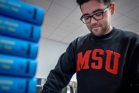 Joziah Lopez organizes a stack of textbooks.