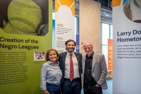 Three people stand in front of banners that provide history at Muth Museum at Hinchliffe Stadium