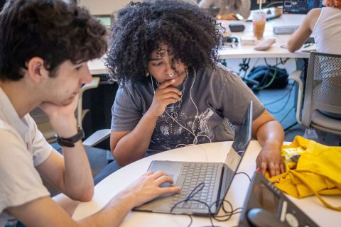two students working together looking at a laptop