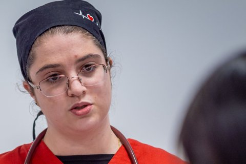 Nursing student is taking notes with a stethoscope around her neck.