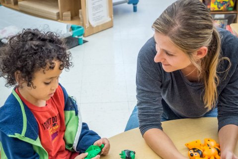 Teacher is talking with a student on a table.