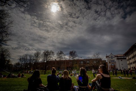 Students sat down on the quad looking at the Eclipse.