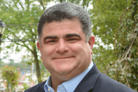 Man is smiling for a headshot with a button down and suit.