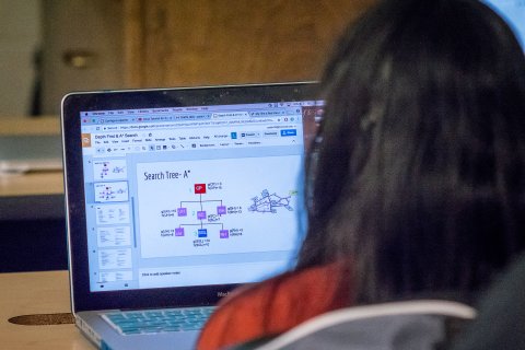 Student working on code and data analysis on a laptop.