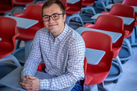 Jacob Roby sits in a classroom full of red chairs.