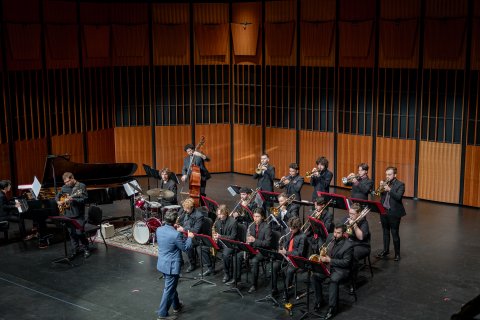Group of students performing with instruments on stage.