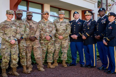 Military personnel posing together with their hands over one another.