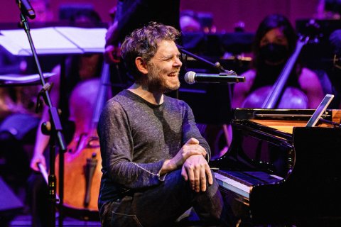 Gabriel Kahane on stage singing into microphone