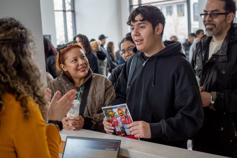 A student in the center, with his parents, talk with a college staff member.