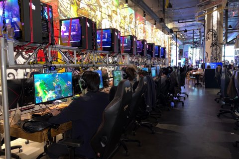 Attendees play video games on computers at a gaming venue.