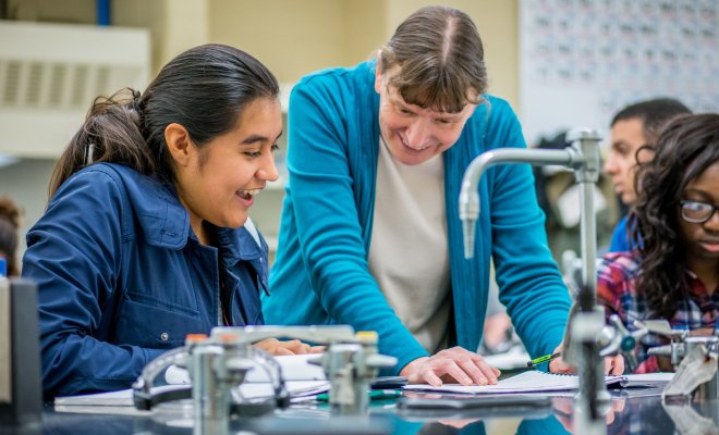 A professor and a student smiling while checking observations in a chemistry lab