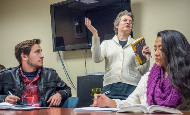 Instructor speaking to class, standing between two students.