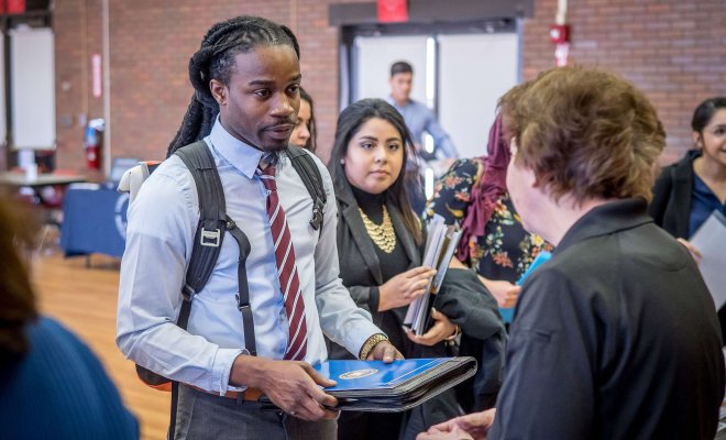 Students at job fair, speaking with a representative.
