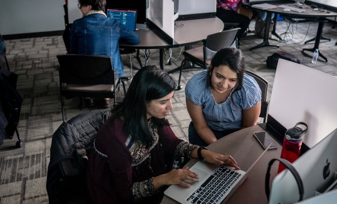 two people looking at a laptop in a computer lab