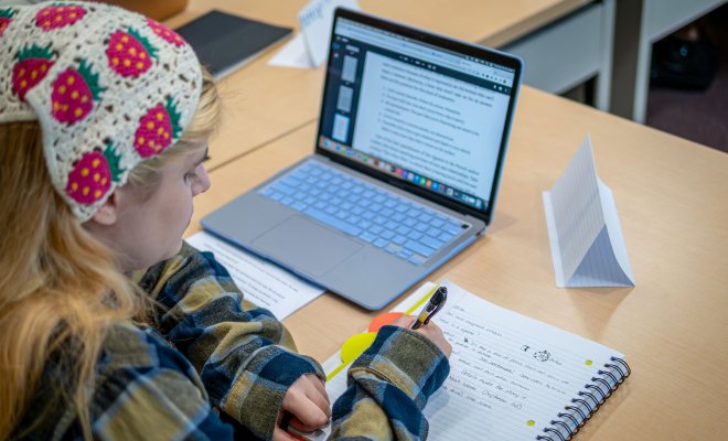 Student writing in notebook during writing workshop.