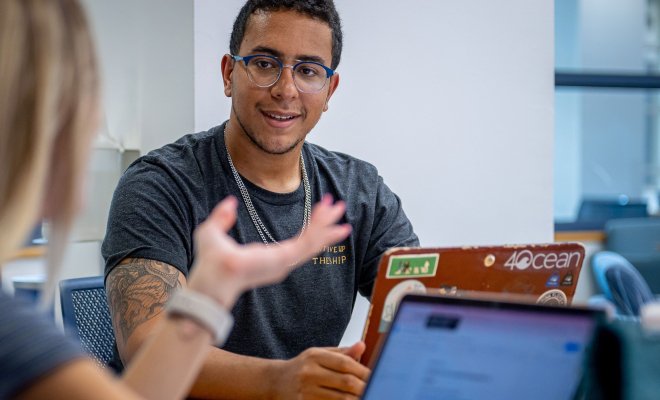 Students talking with laptops in front of them.