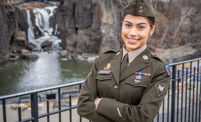 Brianna Correa, wearing her National Guard Army Green Service Uniform, modeled after WWII-era attire, at the Paterson Great Falls, reflecting her strong connection to her hometown city.