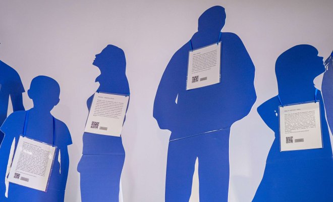 Blue, life-size cutouts of people are displayed in a university hallway. Each cutout symbolizes an individual who is a victim of human trafficking to raise awareness to the issue