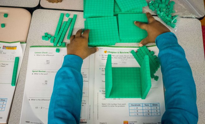 Overhead view of a child working with green blocks to learn the fundamentals of subtraction.