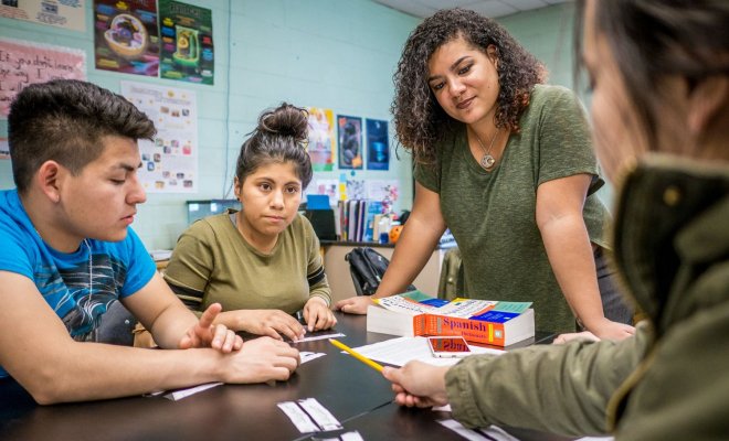 A teacher helps students with a group project.