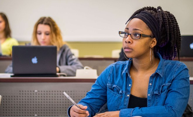Student wearing glasses, taking notes in class.
