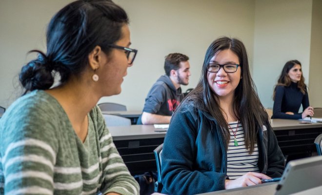 Two people talking to each other in class.
