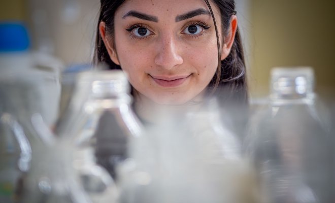 Melissa Spigelman with laboratory glassware in the foreground.