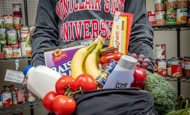 Picture of someone holding a backpack full of fruit, vegetables, and hygiene products. 