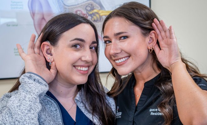 Nicole Genser and Grace Gleba hold their hands to their ears.