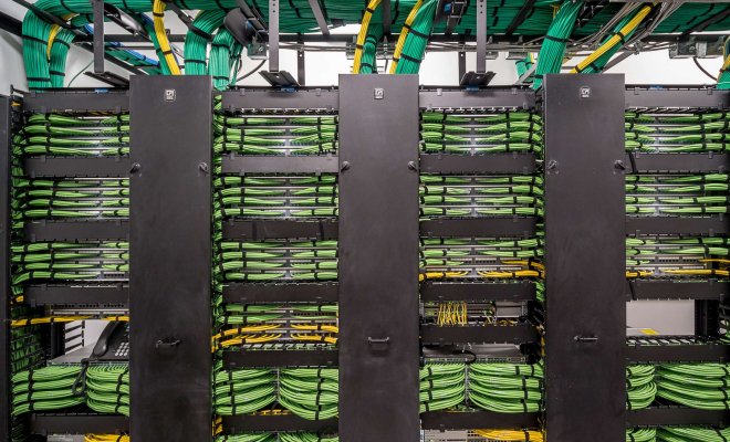 Photo of neatly organized cables going into a rack of servers and networking equipment.