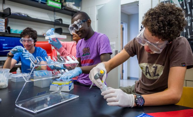Three young students in a lab handling samples.