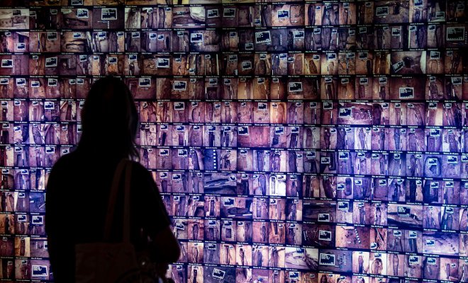 Student stands in front of an illuminated wall displaying an array of burial sites.