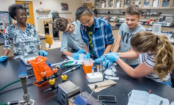 University professor leads a team of four high school students through an experiment in an laboratory.