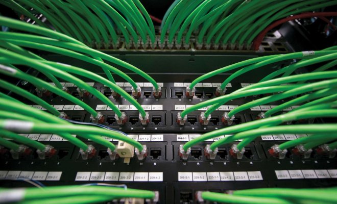An array of green networking cables coming out of a network router.