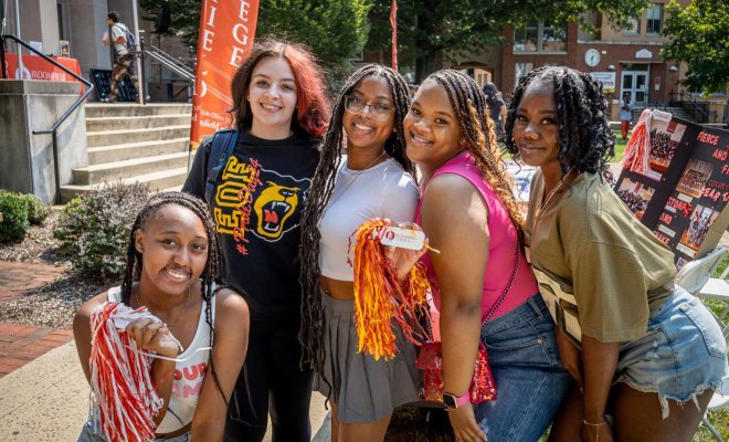 Five female students are pictured smiling close together. 