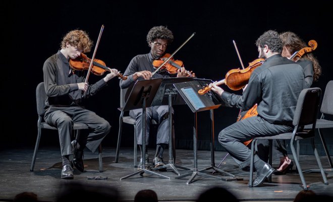 Cali students perform string instruments onstage.