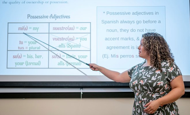A woman points to a screen with Spanish adjectives on it.