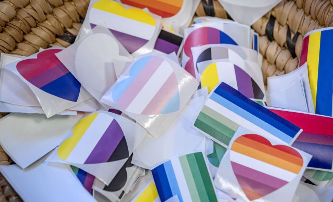 A basket holding LGBTQ+ pride stickers shaped as flags and hearts.