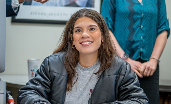 Transfer student Abigail Rodriguez sits at a desk inside a classroom with a notebook in front of her and holding a pencil.