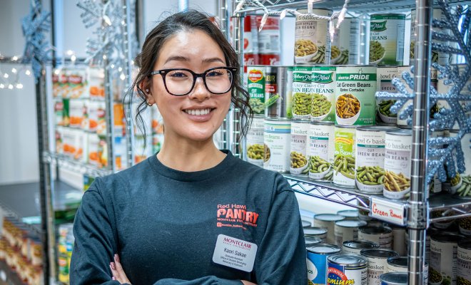 Kaori Sakae stands, arms crossed, in front of food-filled shelves at Red Hawk Pantry.