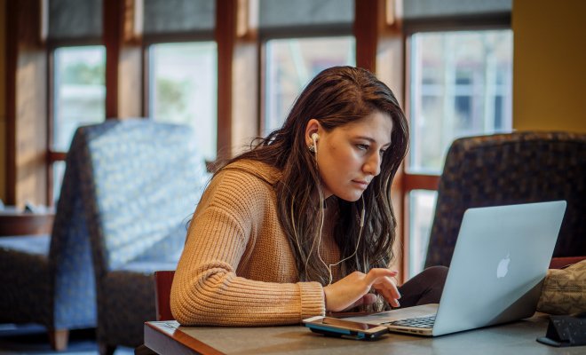 Woman working on a laptop wearing headphones