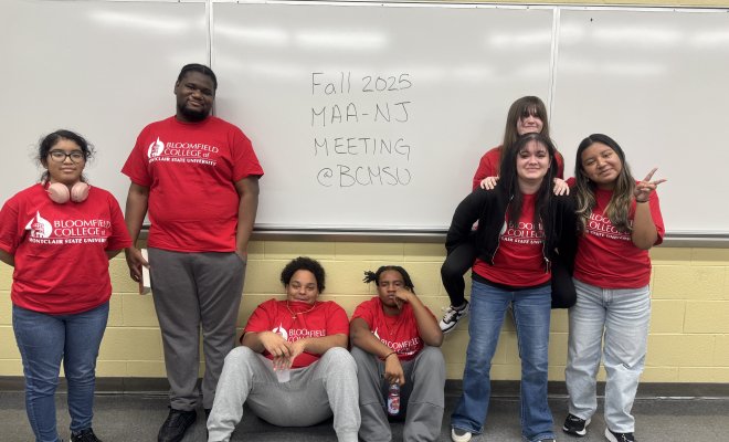 Seven student are pictured posing for the camera, three are standing, two are sitting, one is piggybacking on another. 