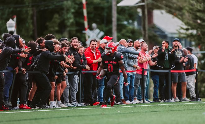A Montclair football player, #0, is hyped up by a crowd of fans.