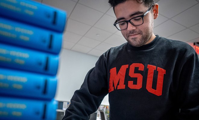 Joziah Lopez organizes a stack of textbooks.