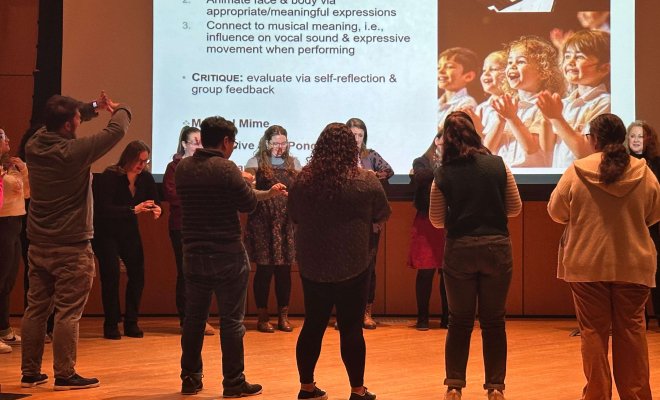 Music education students in a circle on stage.