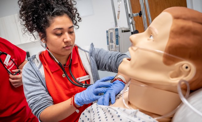 A nursing student uses a mannequin for realistic medical simulations.