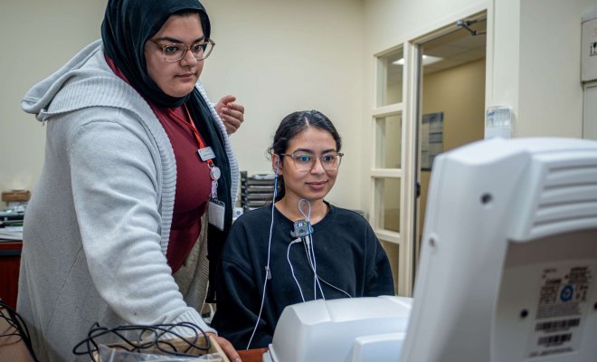 A Speech Language Pathology and Audiology student checks a student’s hearing.