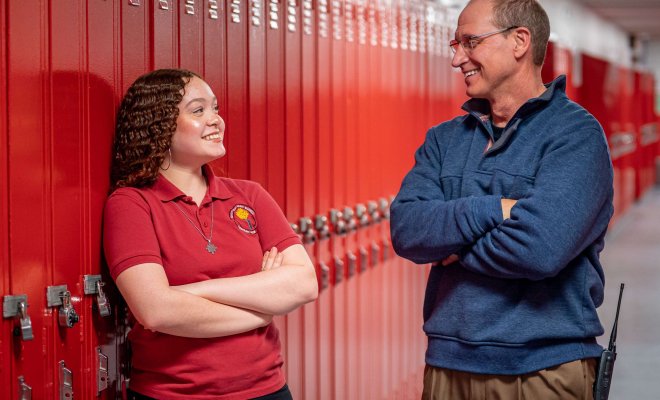 A principal talks with a teacher in a school setting.