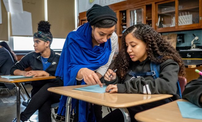 A teacher helps a student with a class assignment.